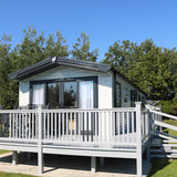 A fully constructed grey end patio deck with a walkway, steps and a gate, attached to a caravan