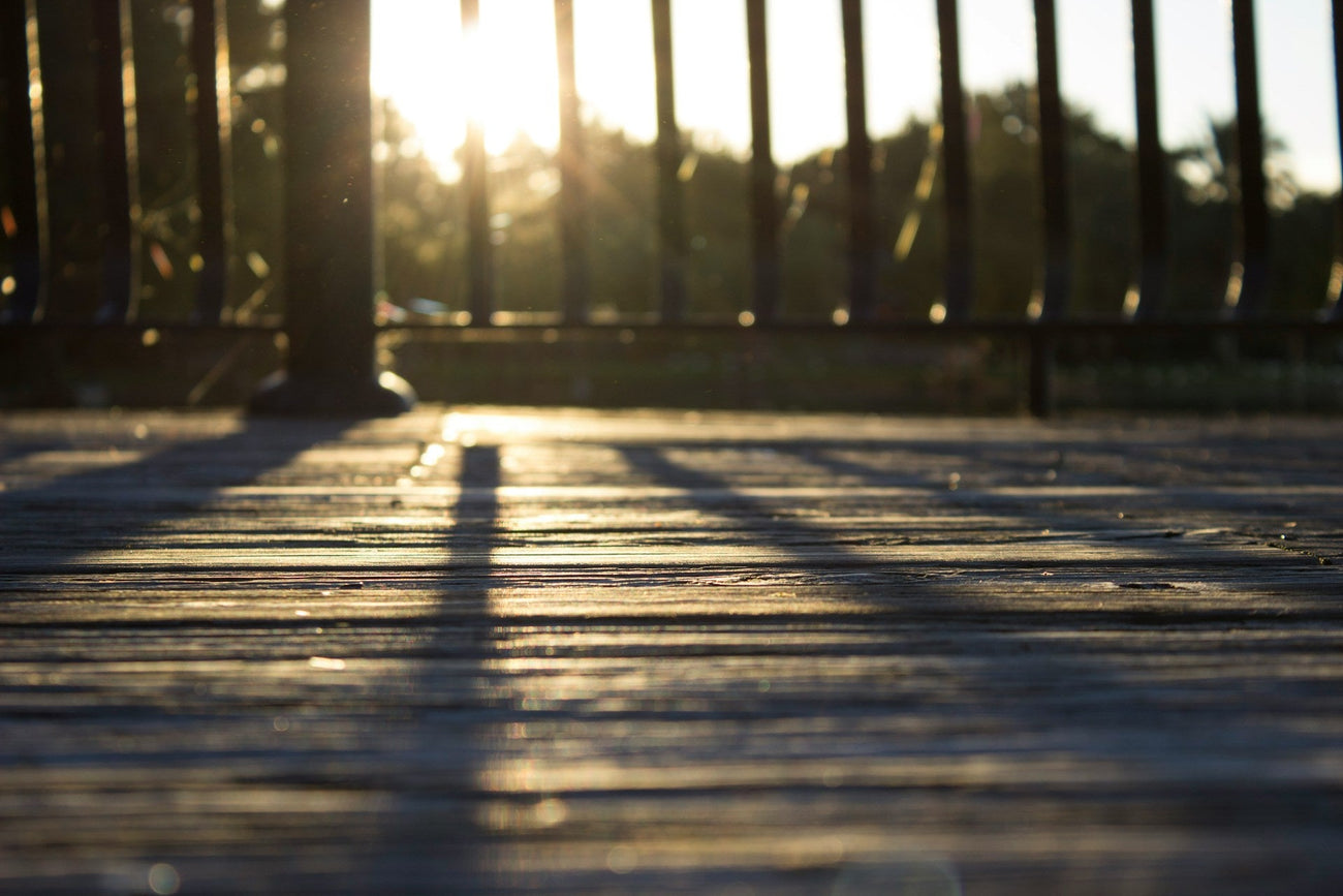 The sun shining through a balustrade onto timber decking